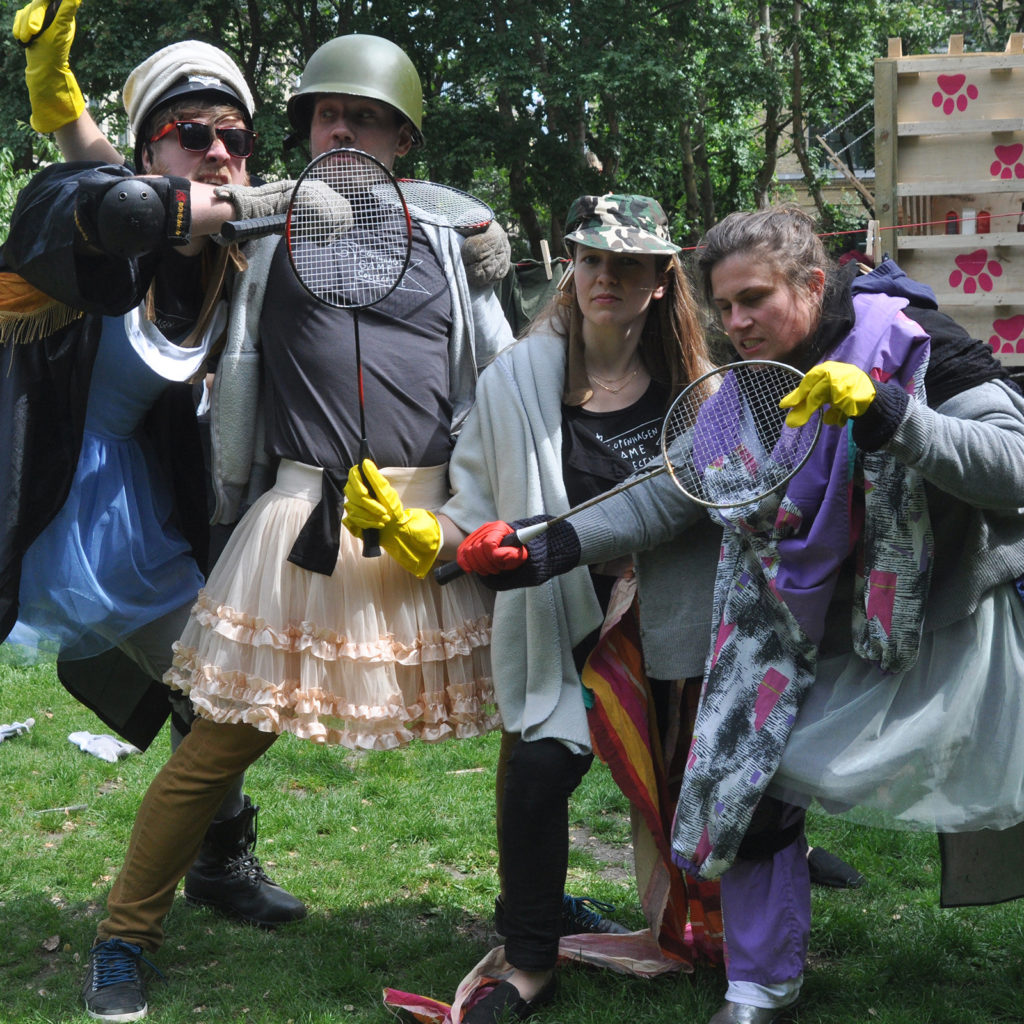 Four players with unique costumes and badminton rackets posing for the camera outside.